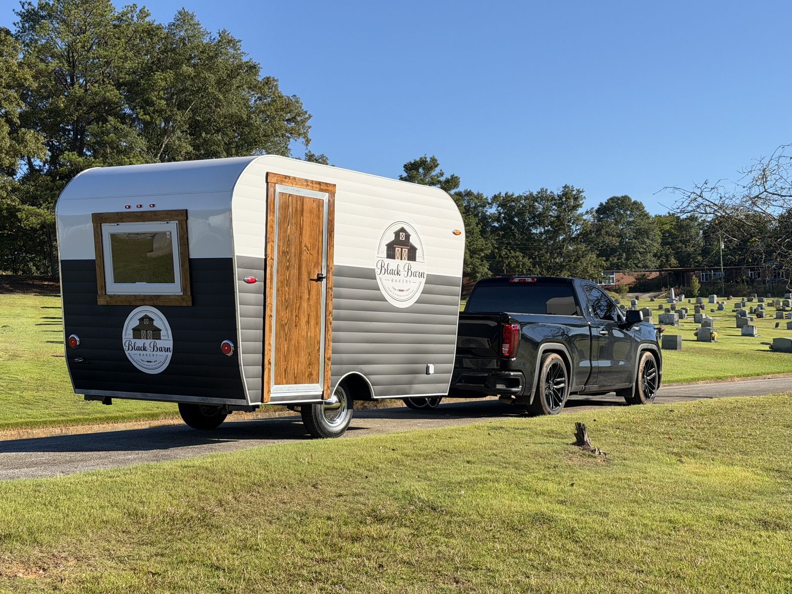 Black Barn Bakery trailer rear three-quarter with wood door and barn logos