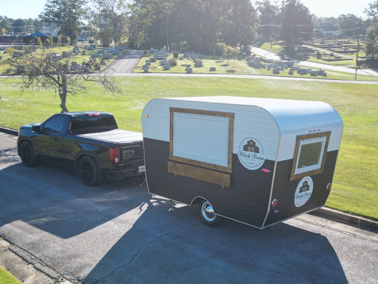 Black Barn Bakery white-and-black canned-ham trailer hitched to a black pickup