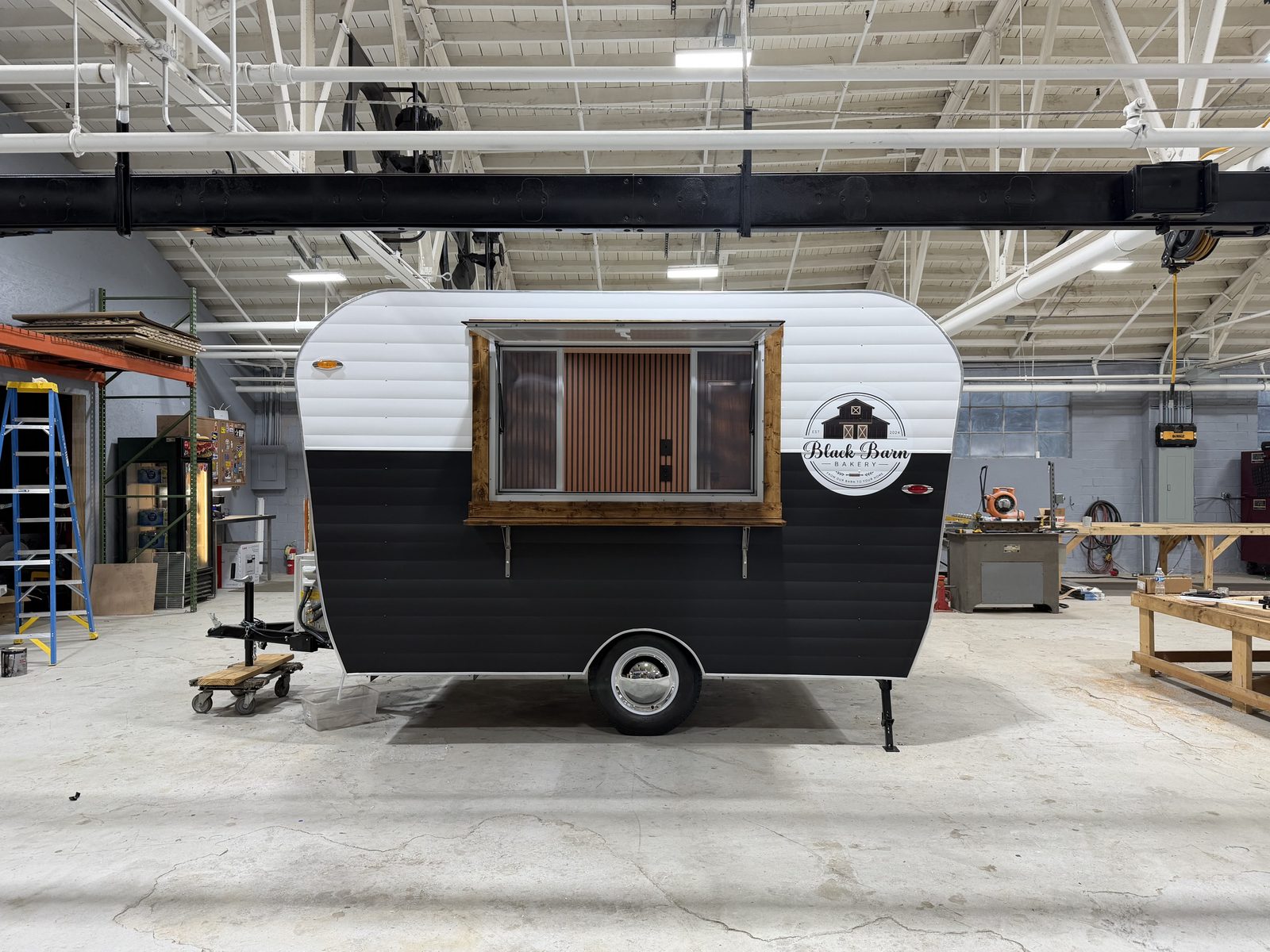 Service side of the Black Barn Bakery trailer with a wood-framed hatch and bakery logo