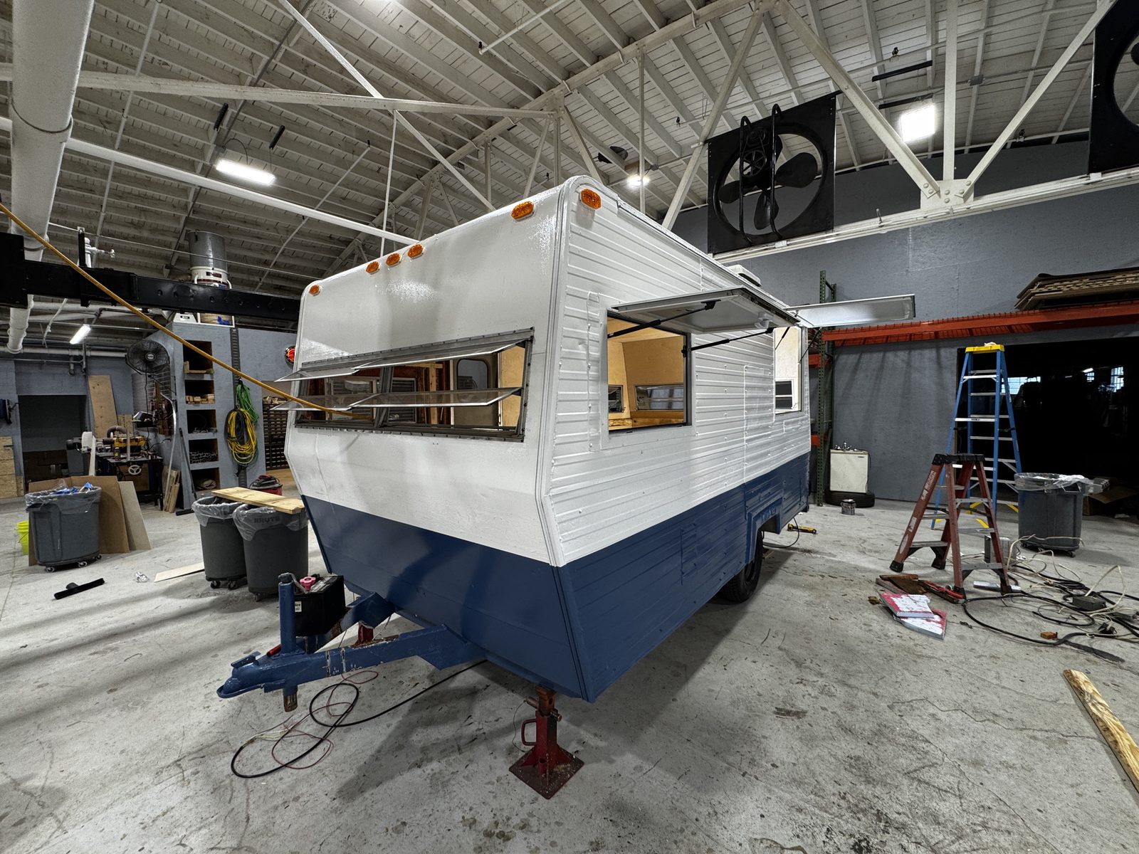 White-over-navy Midas-style trailer in the shop with the service hatch open