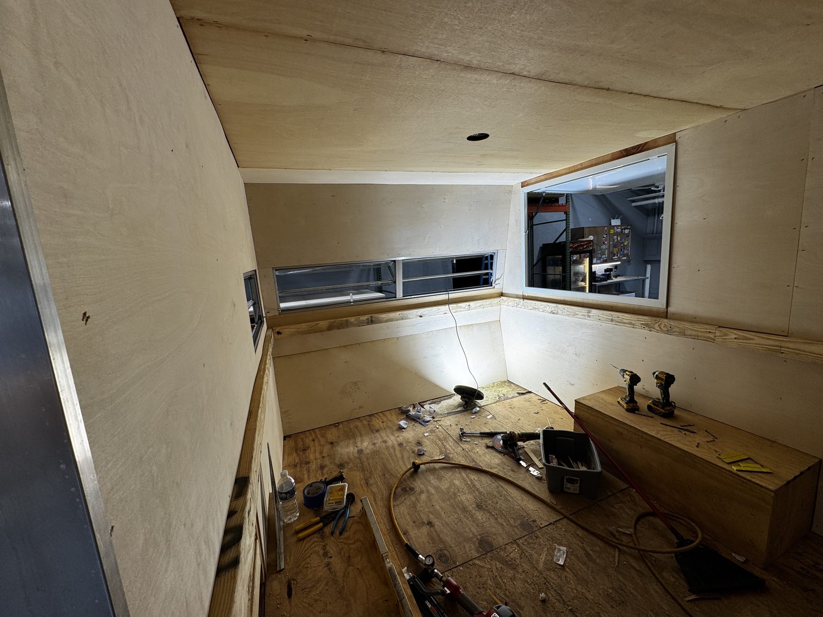 Trailer interior with plywood walls and a rear pass-through window